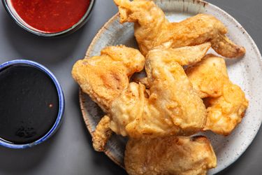 韩国炸鸡翅膀的小板有两个盘子旁边的酱。