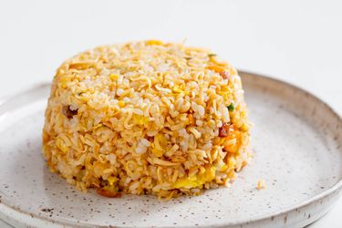 A mound of instant ramen fried rice on a speckled stoneware plate.