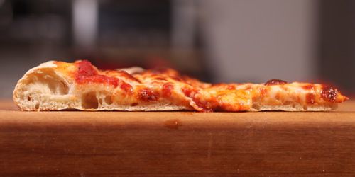 纽约式披萨切片的横截面，饼皮是用食品加工机揉成的面团制成的，口感细腻。gydF4y2Ba