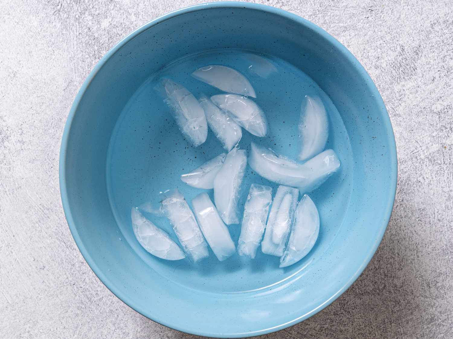 一个蓝色的碗里装满水和冰块，做一个水浴，用来冷却热的熟鸡蛋。