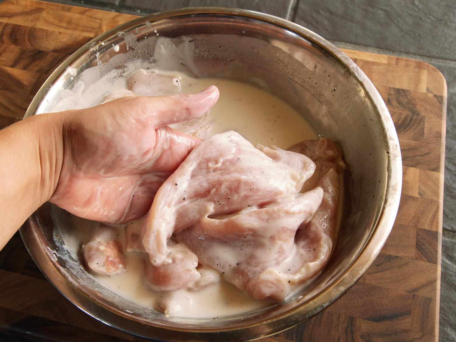 Adding flattened chicken breast to seasoned buttermilk brine