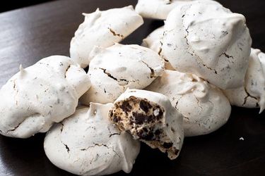 Pile of chocolate chip meringue cookies with cross-section view of cookie's interior