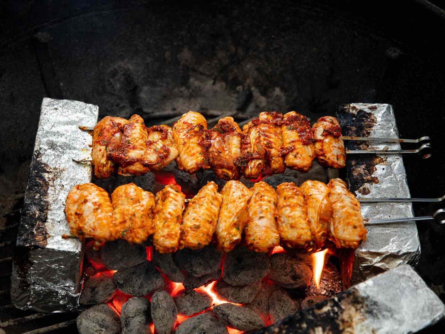 用锡箔包着的砖烤串在热炭上烤土耳其风格的鸡翅。