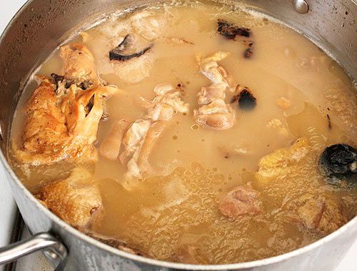 鸡肉和猪骨漂浮在乳白色、不透明的高汤中。