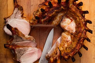 A crown roast of pork on a cutting board, three chops have been cut from the roast.
