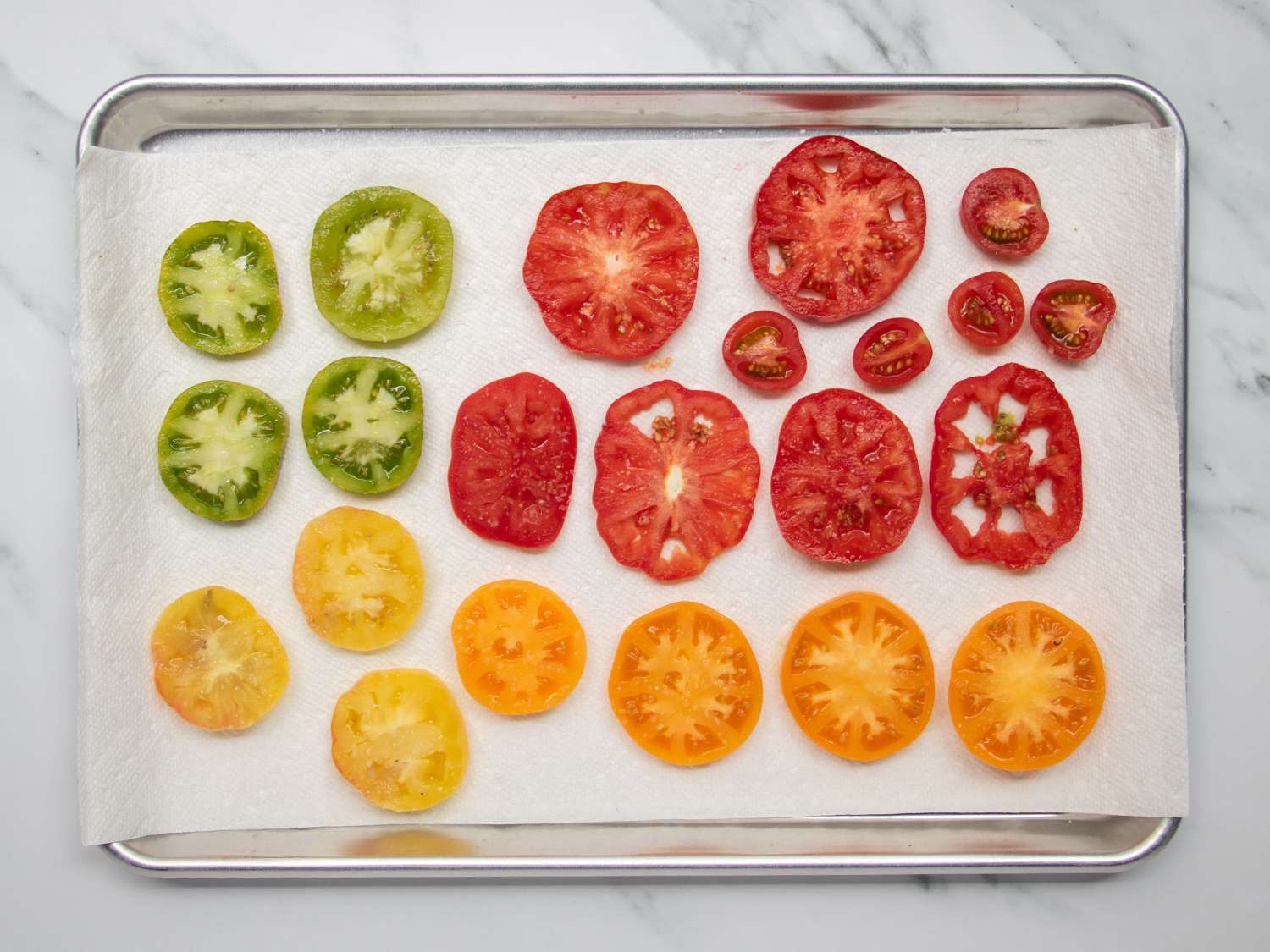 将不同种类的西红柿切片放在有纸巾衬里的烤盘上