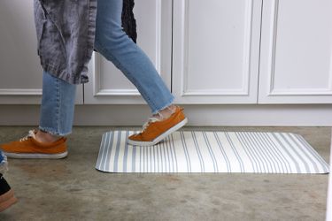 A person walking across a stripped anti-fatigue mat on a kitchen floor