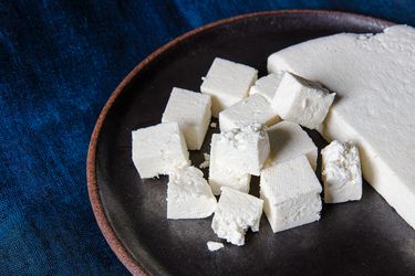 Fresh paneer on a brown plate on a blue backdrop
