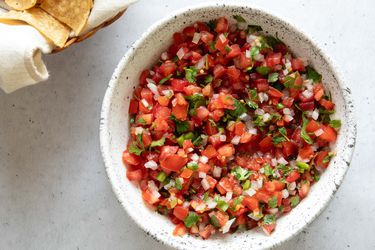 a bowl of pico de gallo with tortilla chips on the side
