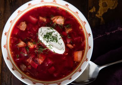 Overhead shot of a bowl of Ukrainian borscht topped with a dollop of sour cream and sprinkling of fresh dill