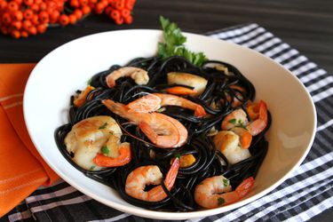 A bowl of black squid ink pasta with shrimp and scallops