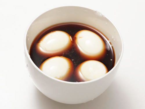 四个半熟的鸡蛋浸泡在酱油混合物中，在一个白色的碗里。gydF4y2Ba