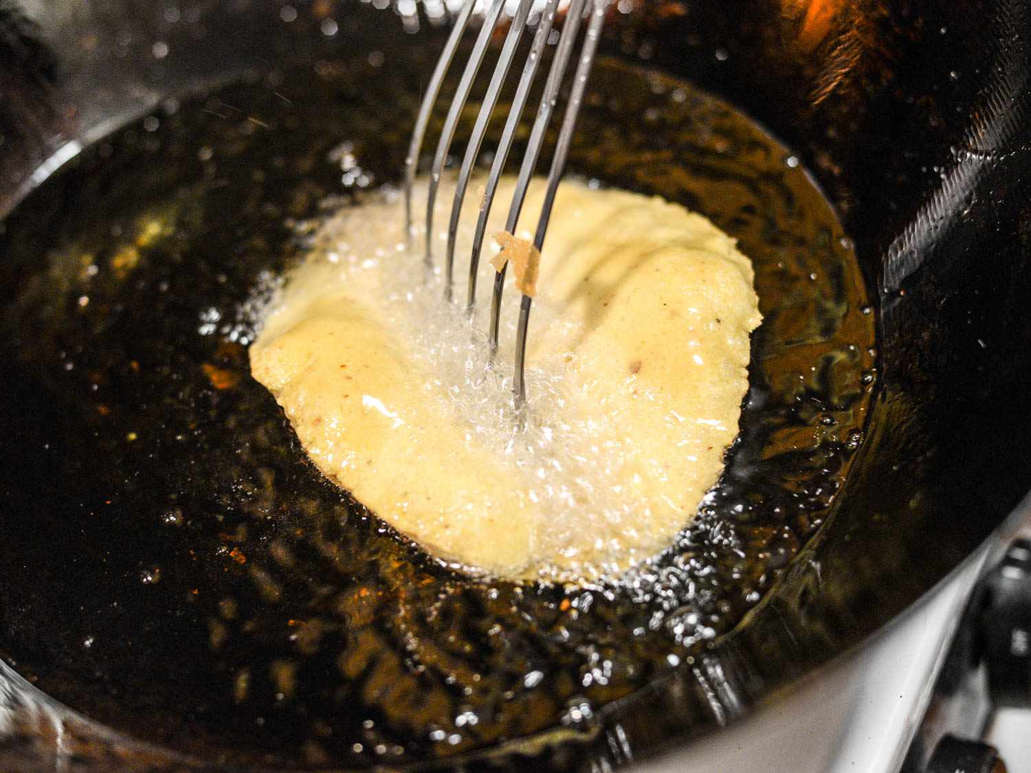 用金属抹刀将油炸好的玉米饼压成玉米饼的形状。