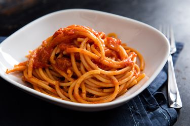 A square white bowl of bucatini all'Amatriciana.