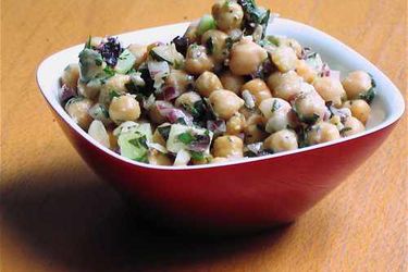 A red square bowl filled with Greek-style chickpea salad.