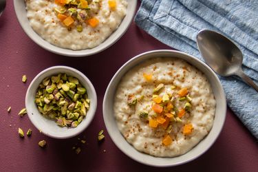 vanilla rice pudding in two bowls topped with dried apricots and pistachios