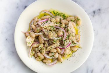 White bean, tuna, and pickled red onion salad on a white plate