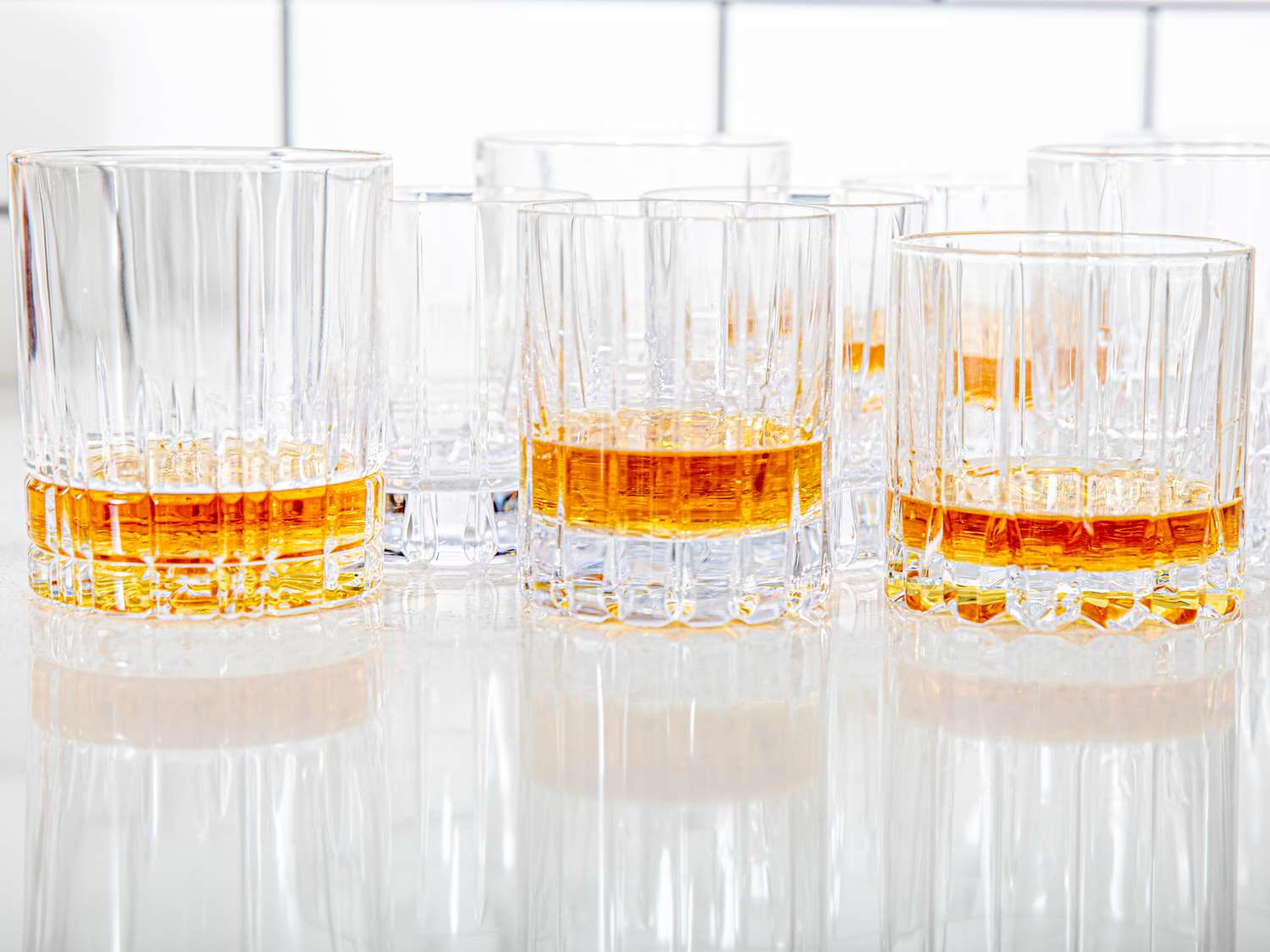 numerous rocks glasses with whiskey in them on a kitchen countertop