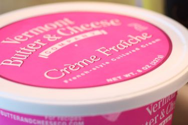 一个粉红色和白色的crème fraîche容器的特写。＂width=