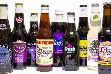 A collection of assorted grape sodas in bottles.