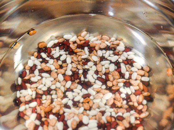 A bowl of mixed dried beans soaking in water