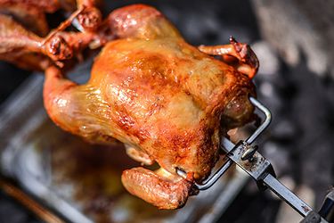 A rotisserie chicken rotating on a spit.