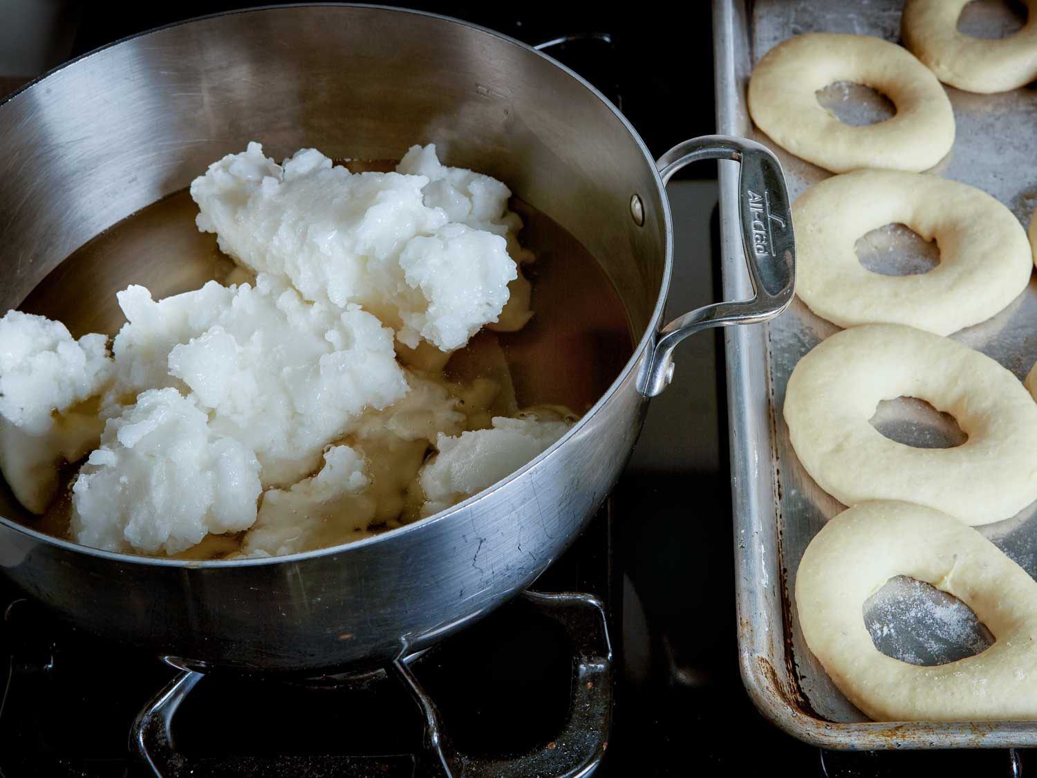 在一个大的荷兰烤箱中放入固态椰子油，融化一半，旁边放一盘甜甜圈面团gydF4y2Ba