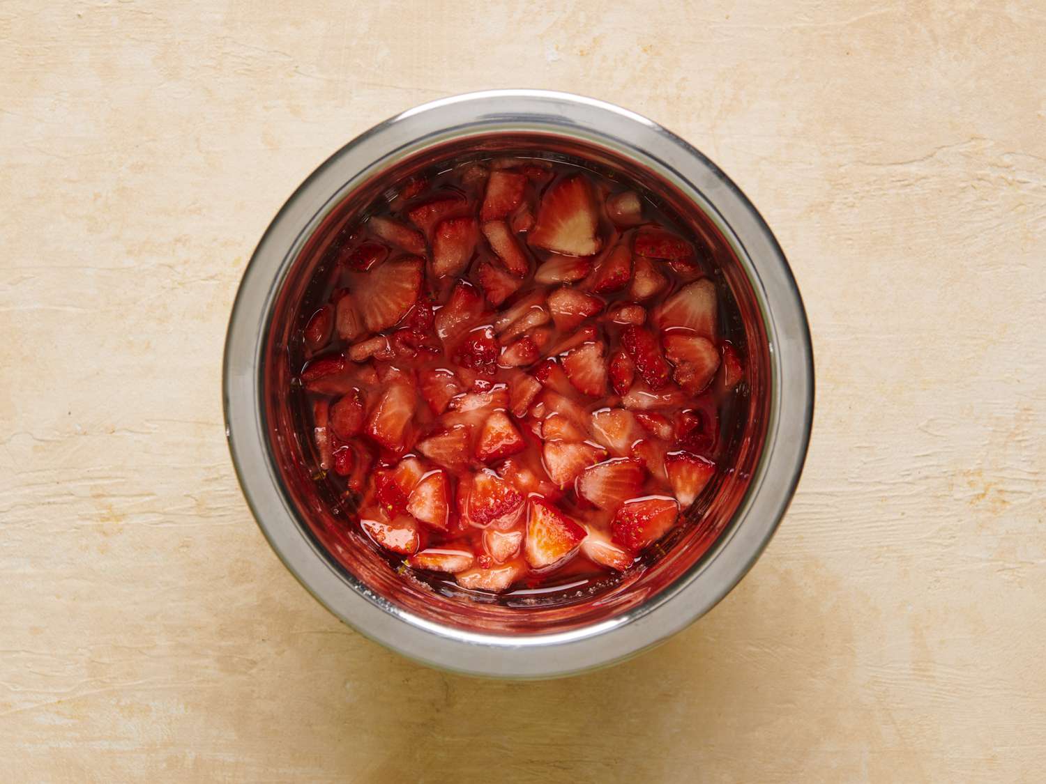 Quartered strawberries, Â½ cup of sugar, and alcohol combined in a non-reactive mixing bowl.