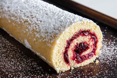 An old-fashioned jelly roll sprinkled with powdered sugar on a baking sheet.