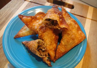 A plate of Somali sambusas, with one broken open to show the beef filling.