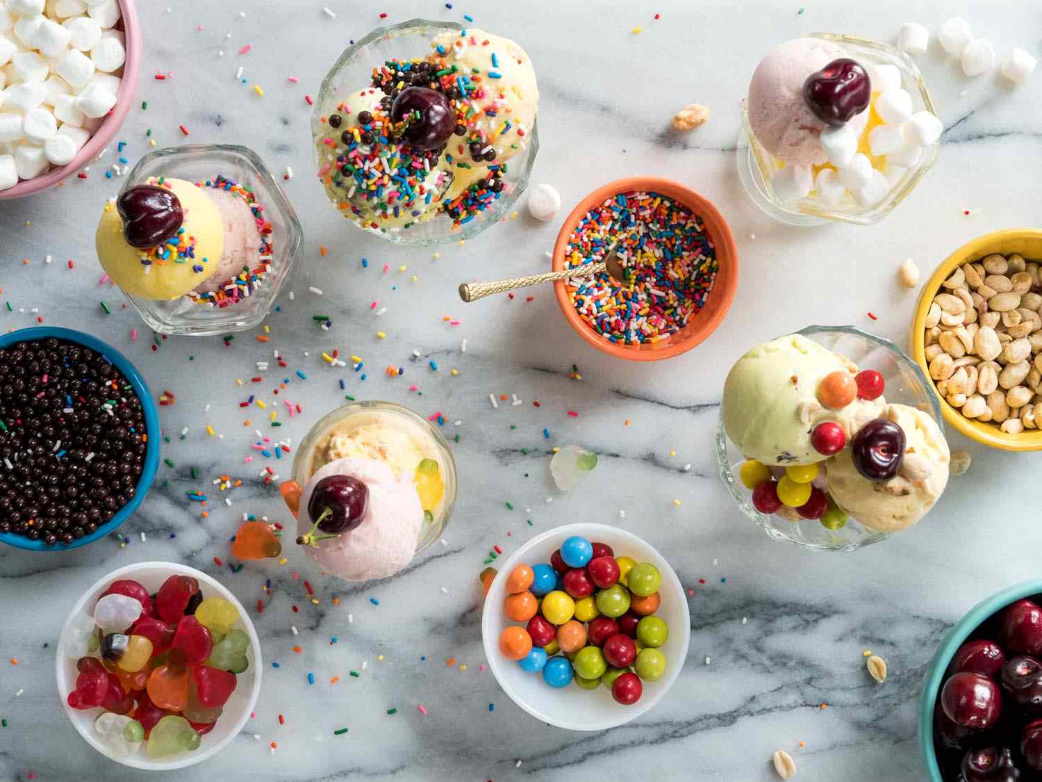 一小碟各色冰淇淋，上面撒上糖屑、糖果、坚果和水果