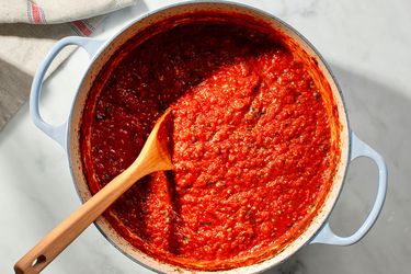 一锅意大利美式番茄酱，用木勺放在荷兰烤箱里。gydF4y2Ba