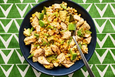 Overhead view of avocado and chicken salad on a green triangle patterned backdrop