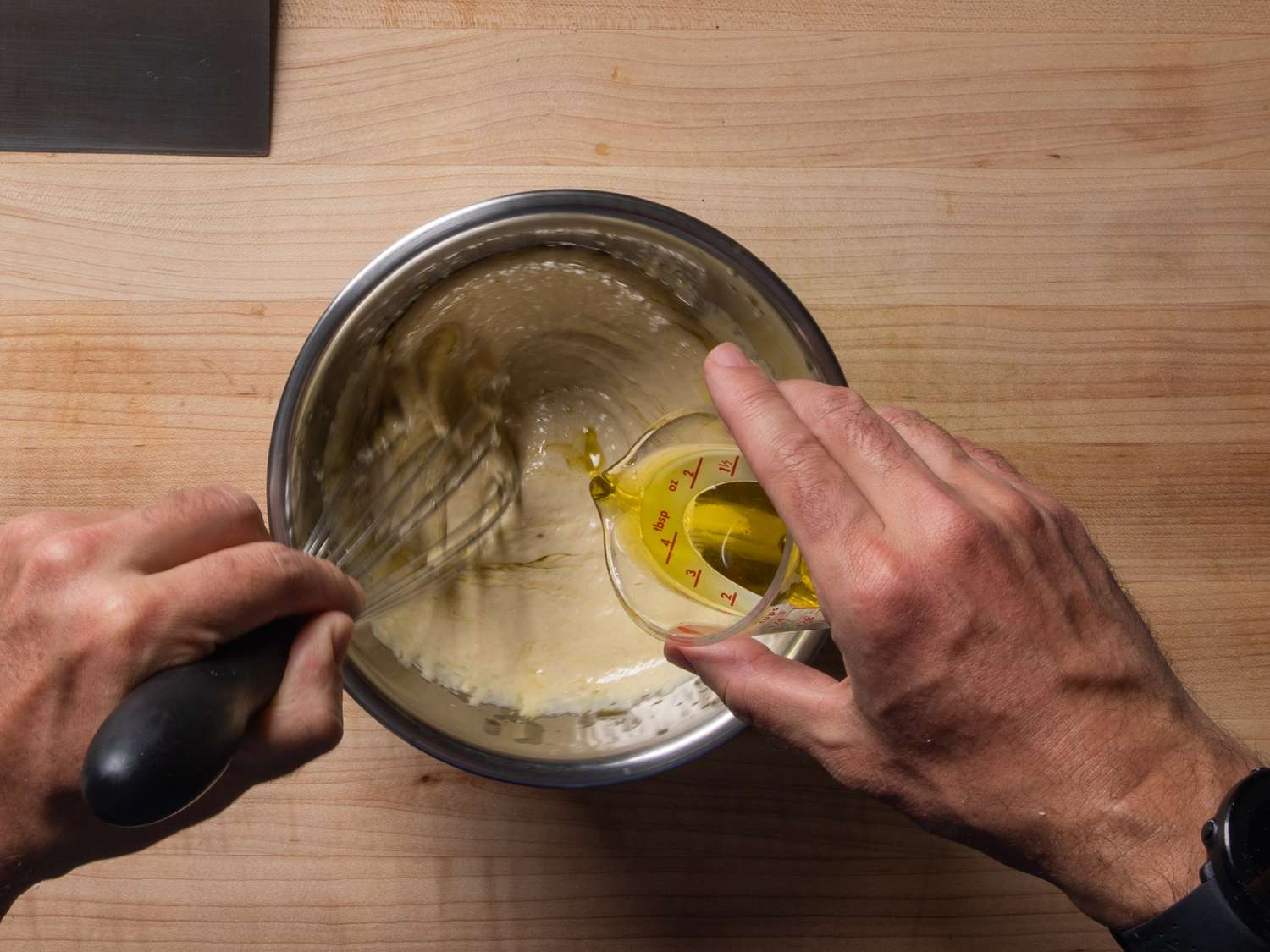 在搅拌碗中，一边搅拌，一边将橄榄油淋入调料中。